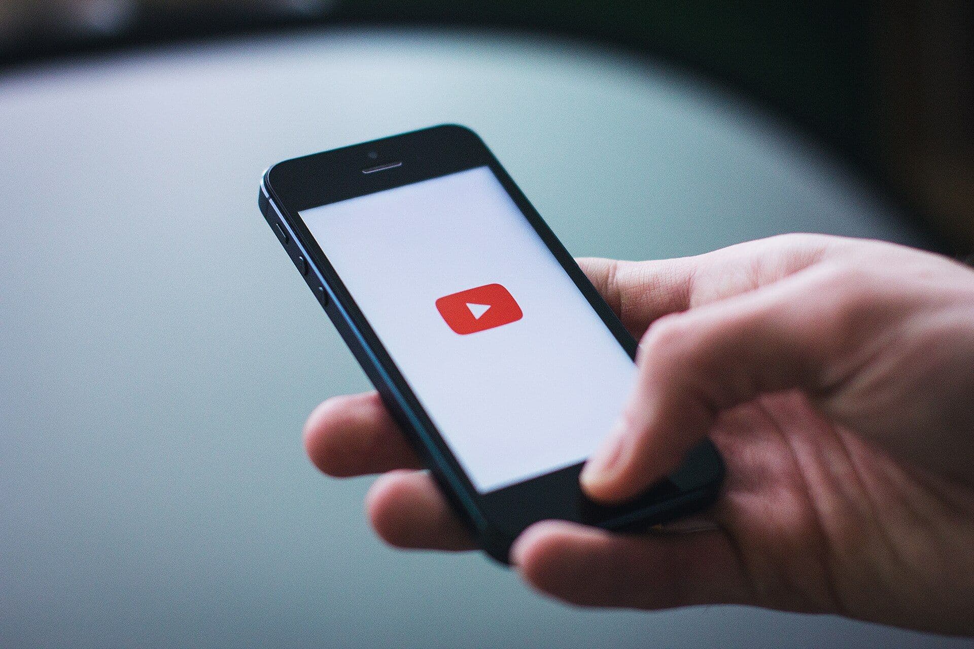 Elinde tuttuğu akıllı telefonda YouTube uygulamasını açan bir kullanıcı