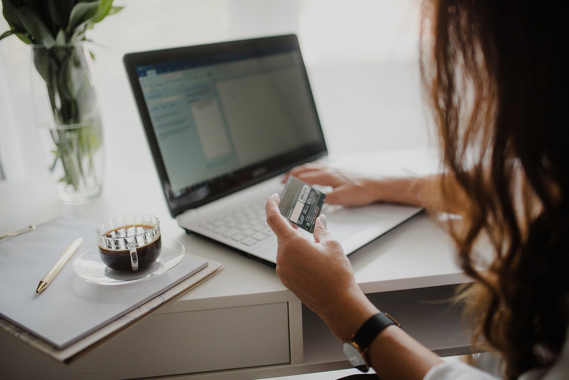 Dizüstü bilgisayar başında kredi kartıyla online alışveriş yapan bir kişi